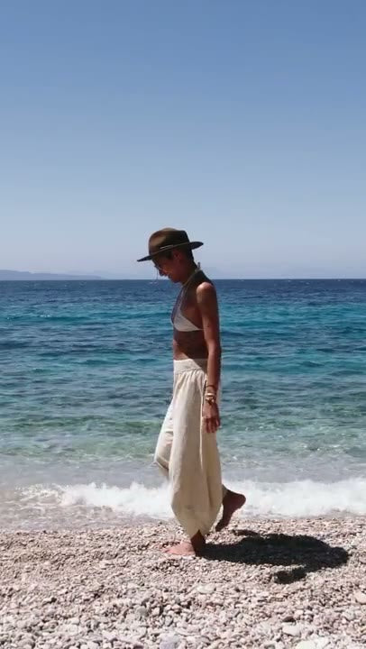 Walking the shoreline in cream flowy pants, Bali dry season