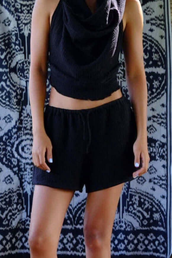 Model wearing black cotton bubble shorts paired with a matching top, showcasing a relaxed summer look.