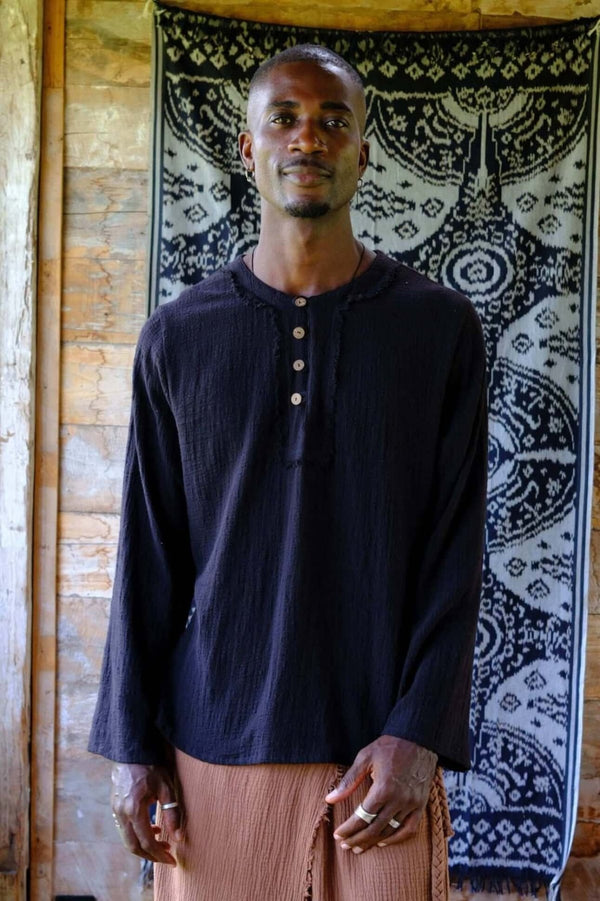 Model wearing a relaxed black cotton yoga shirt with a henley placket and clean lines, perfect for mindful dressing.