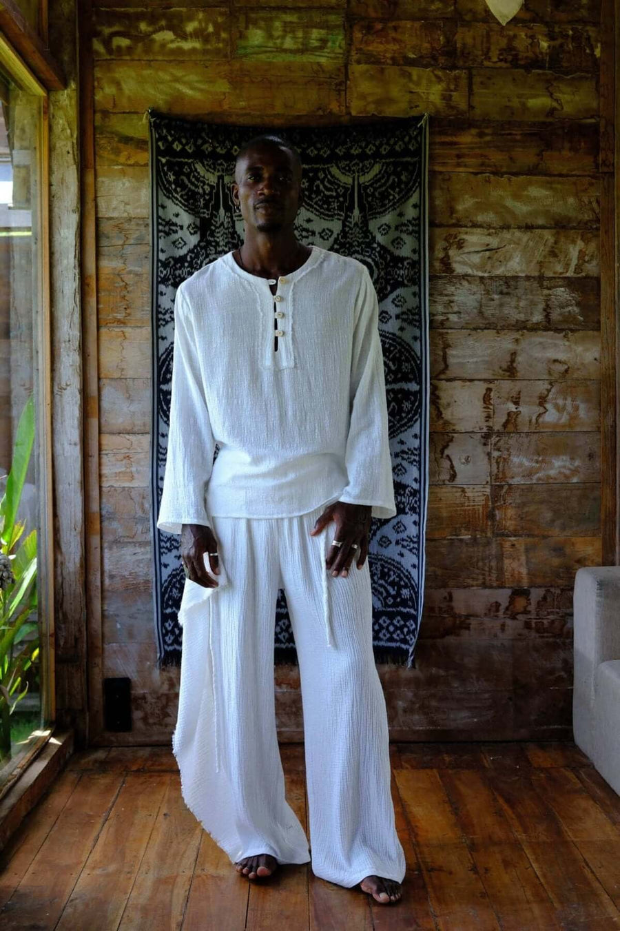 Nahara Pants White - Men worn by a model in a wooden interior, showcasing a relaxed and stylish summer look.