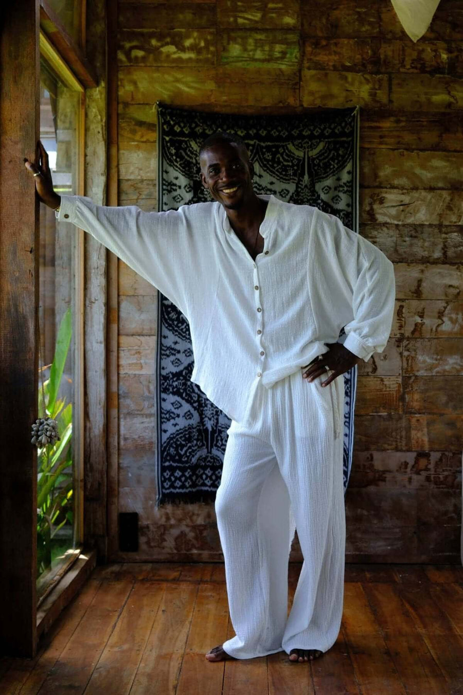 Nahara Pants White - Men worn by a model in a wooden interior, showcasing relaxed style and comfort.
