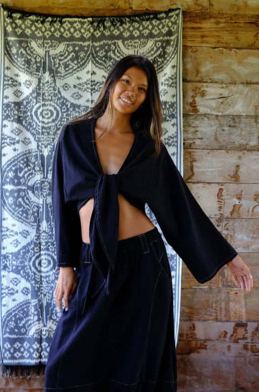 Model wearing a Night Wrap Outline Top with linen shorts, showcasing summer resort wear style in a relaxed setting.