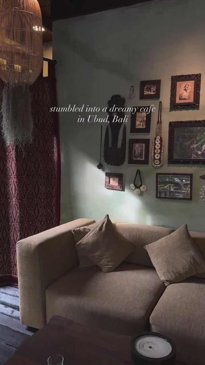 A cozy corner of a dreamy cafe in Ubud, Bali featuring stylish decor and a comfortable sofa.