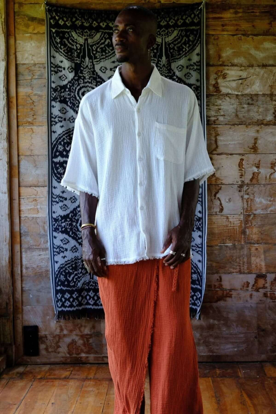 Model wearing a White Gauze Short Sleeve Shirt paired with relaxed orange pants, showcasing a Bali-inspired summer look.
