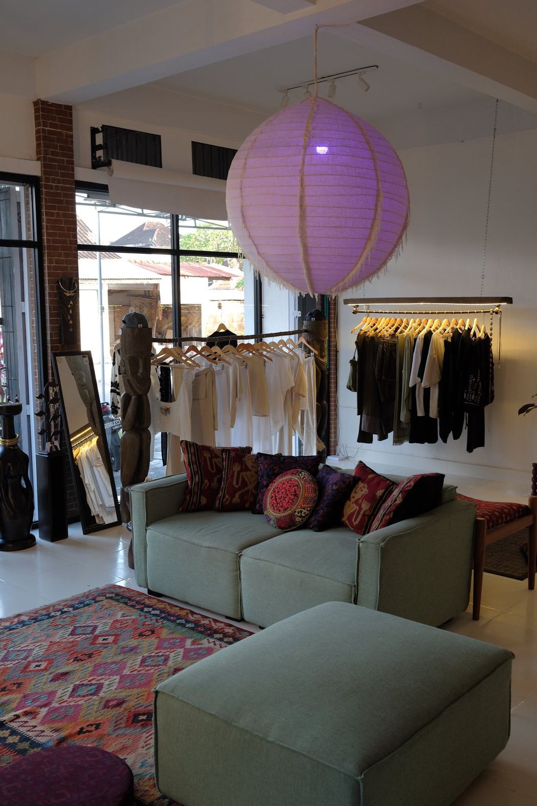 Inside the SNUG showroom in Munggu, Bali — clothing rails, woven textiles and a sage green sofa